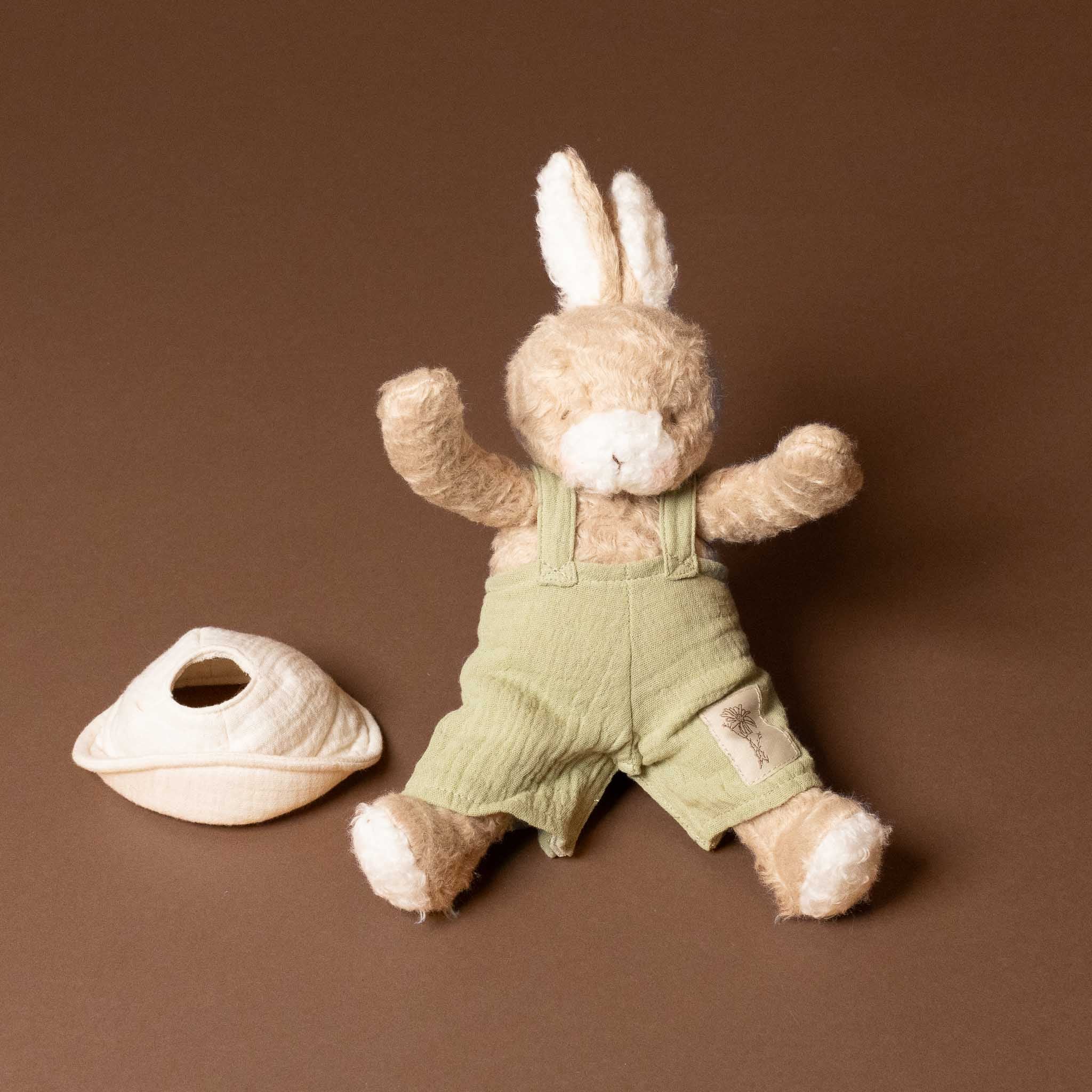 Stuffed bramble-the-bunny-limited-edition with green overalls and white hat on a brown background