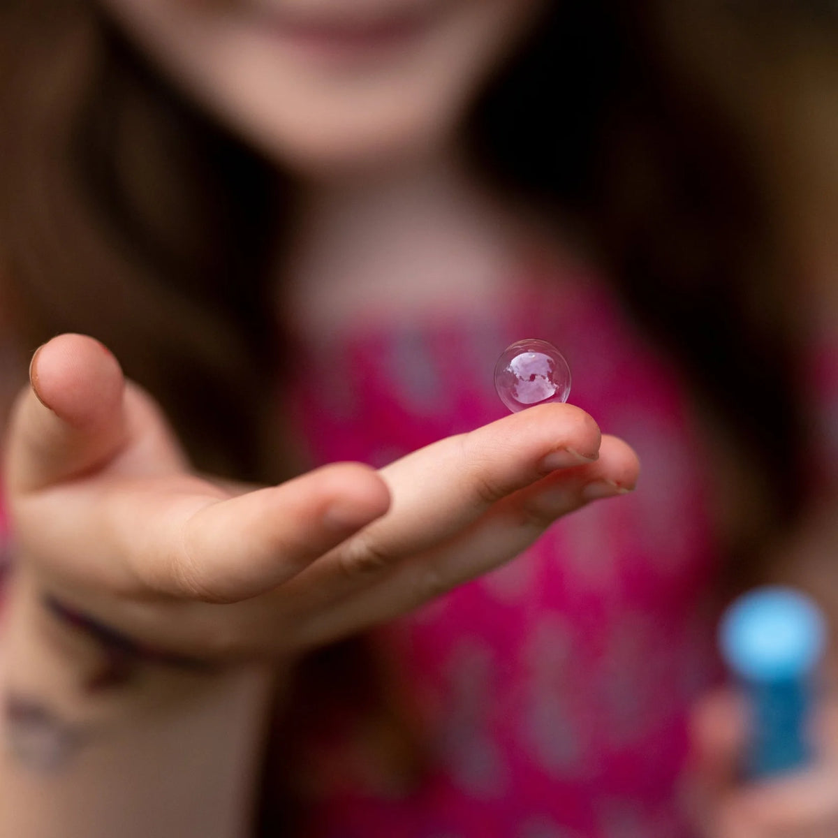 Person holding a small transparent bubble 
