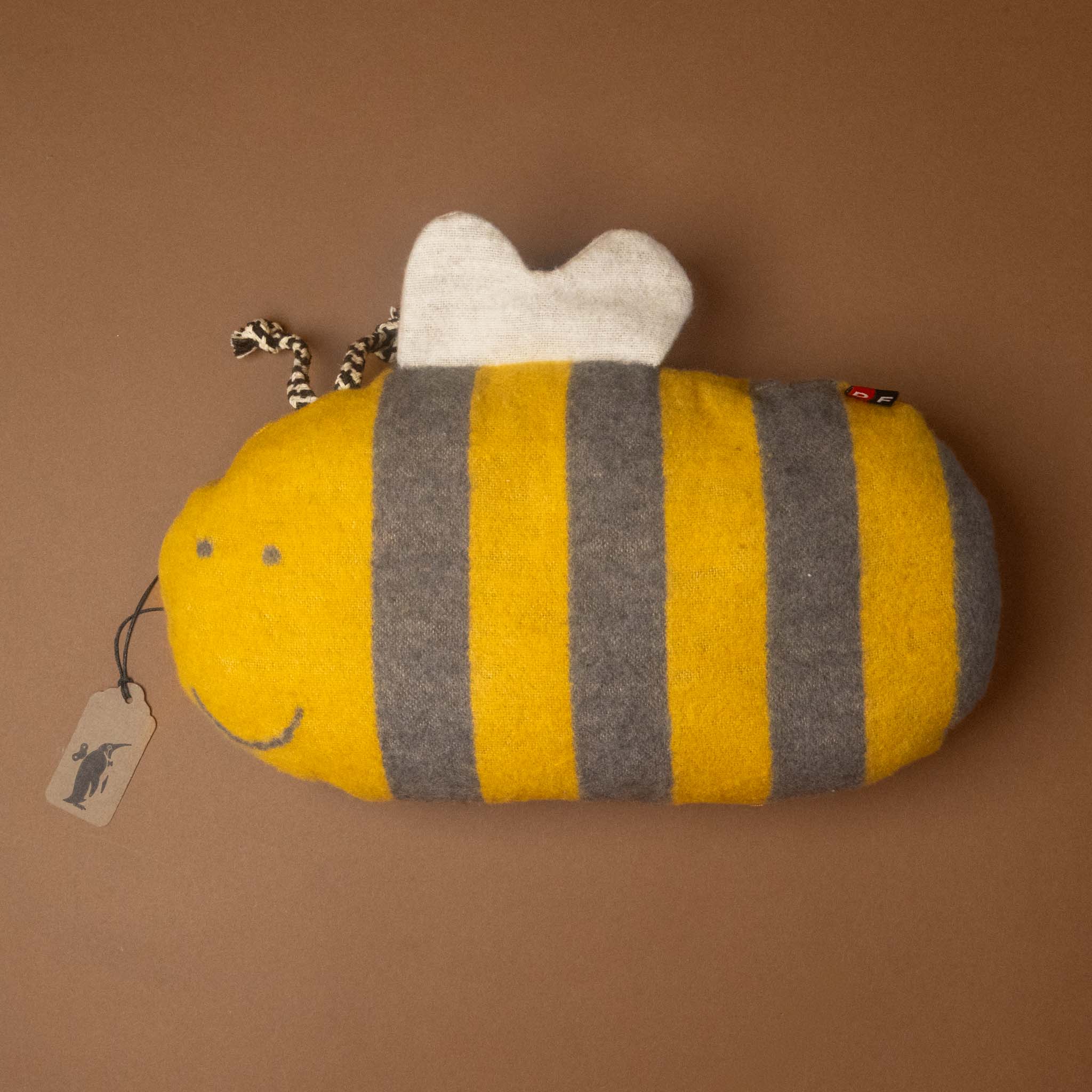 bumble-bee-cushion-pillow with yellow and gray stripes on a brown background