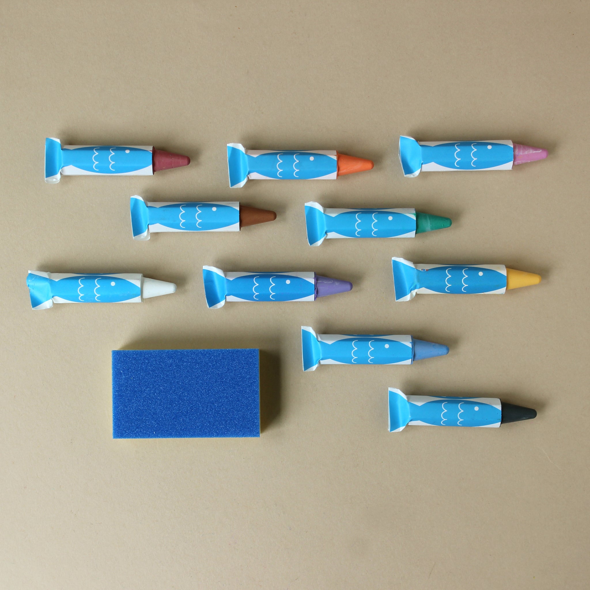 Set of colorful bath crayons with blue fish cover on a beige background