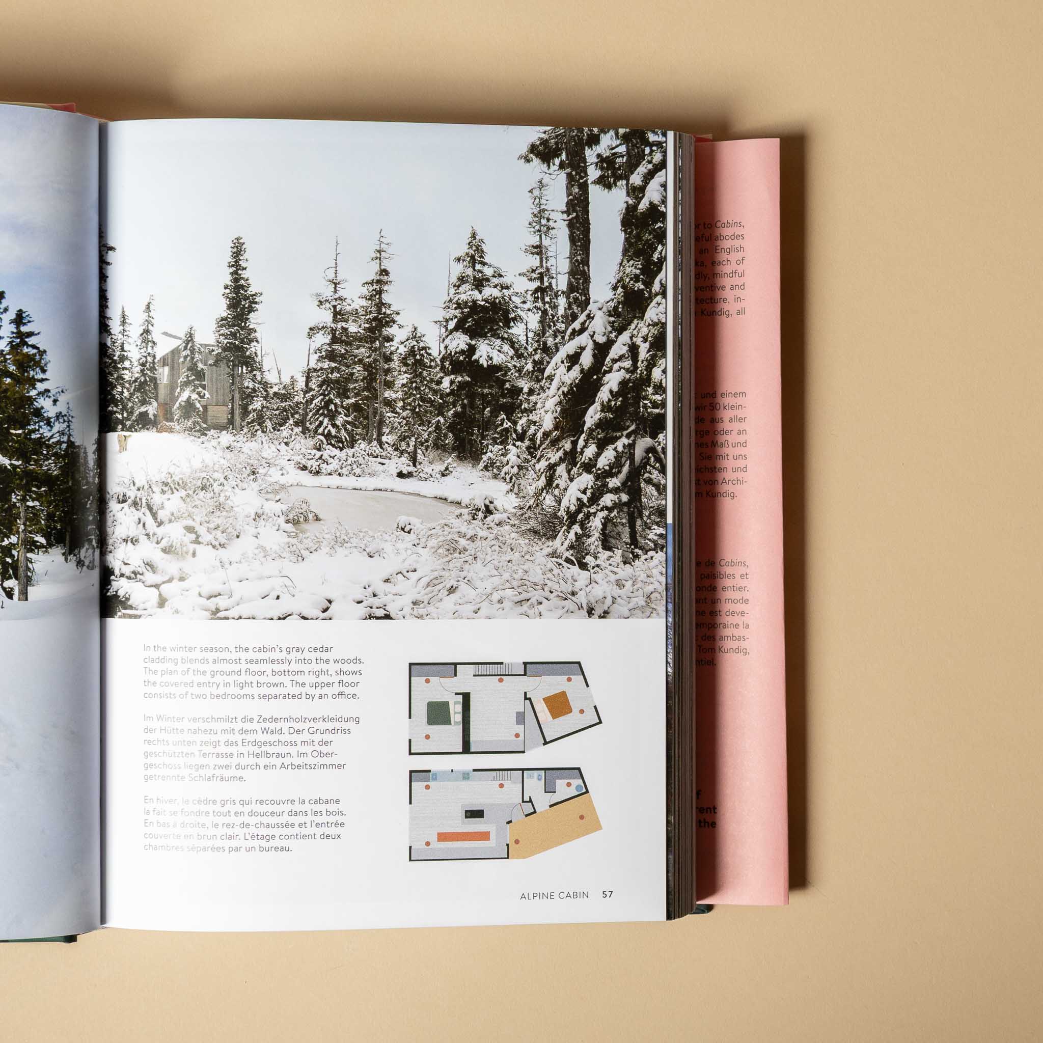 cabins Open book showing a snowy landscape and floor plans on a beige background