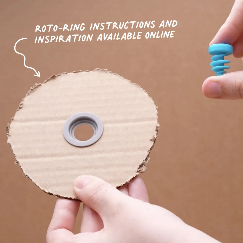 Cardboard roto-ring with a hand holding a blue tool against a brown background