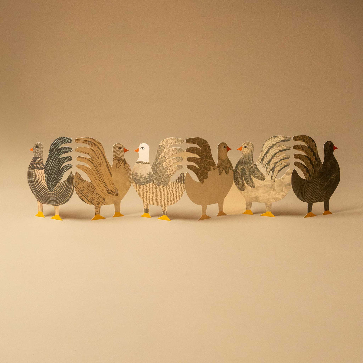 A row of seven stylized bird cutouts or figurines in neutral earth tones, arranged side by side on a plain beige studio background.