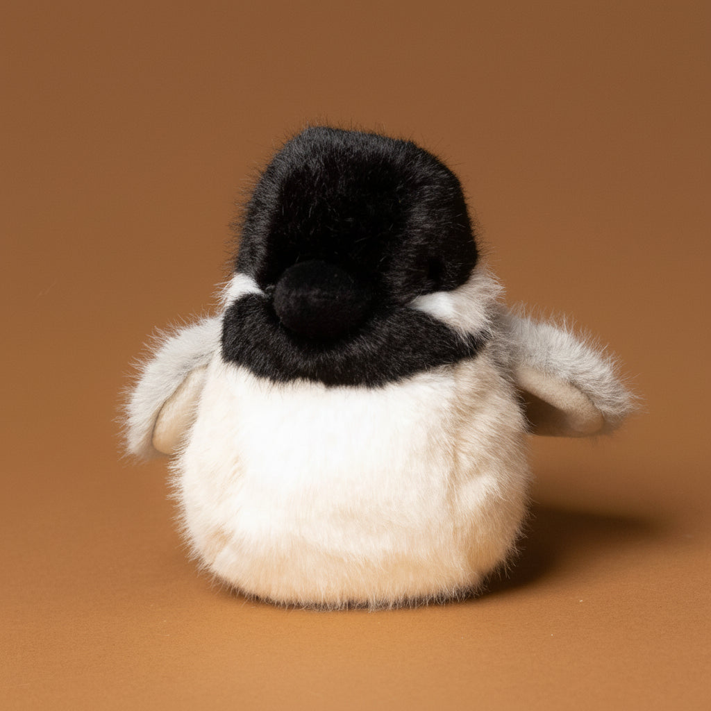 Plush toy chipper-the-chicakdee- with a black head and gray body on a brown background