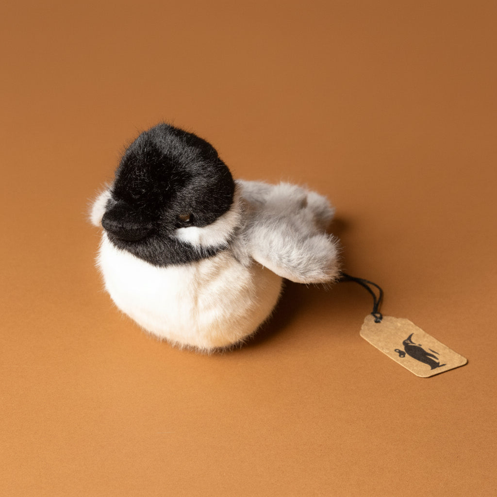 Plush toy chipper-the-chicakdee- with a black head and gray body on a brown background