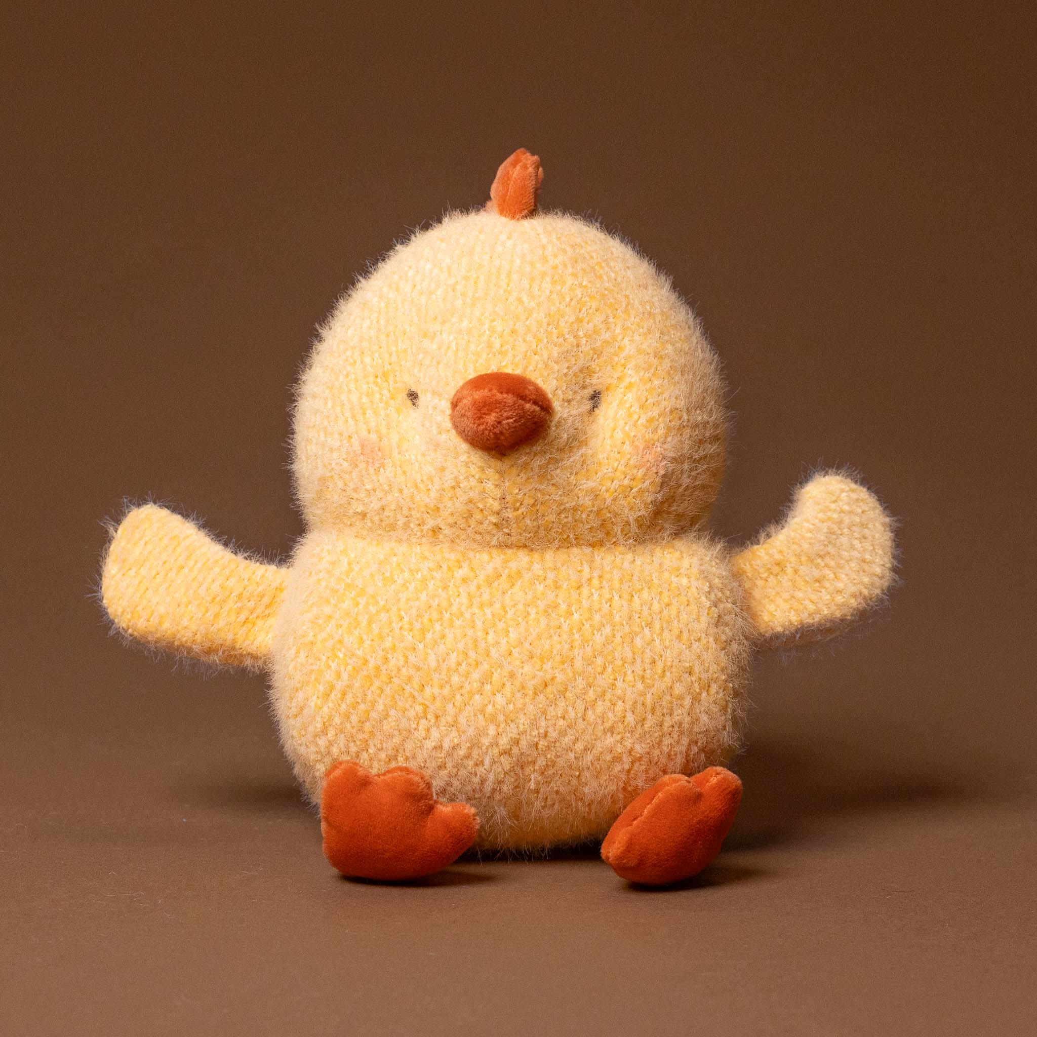Plush toy chick on a brown background