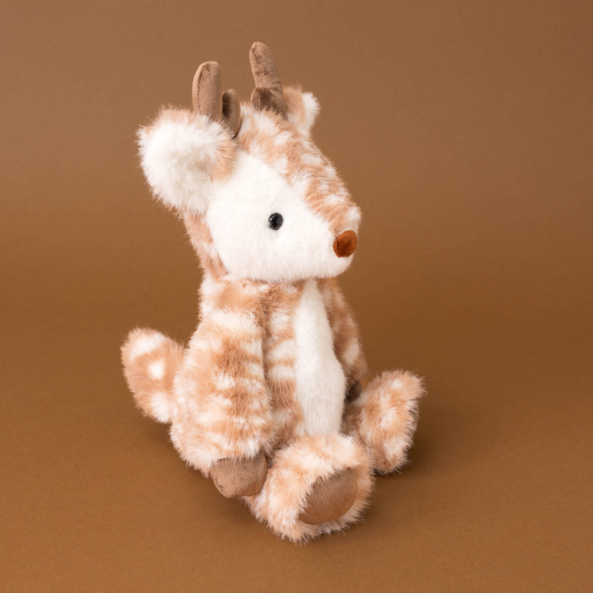 A plush stuffed deer toy with light brown and white stripes, brown antlers, and a small brown snout, sitting against a solid brown background.
