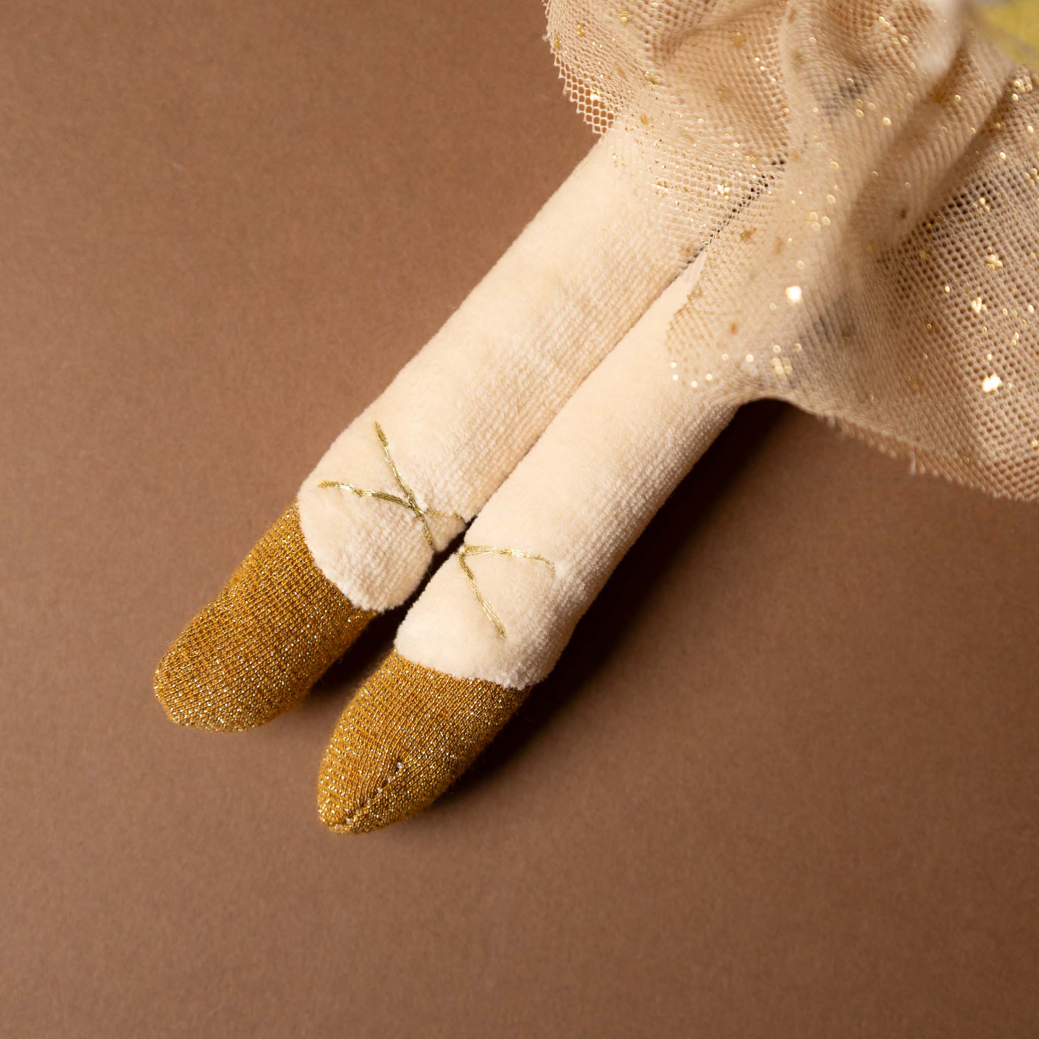 dance-mouse-golden-belle Close-up of a beige glove with gold tips on a brown background
