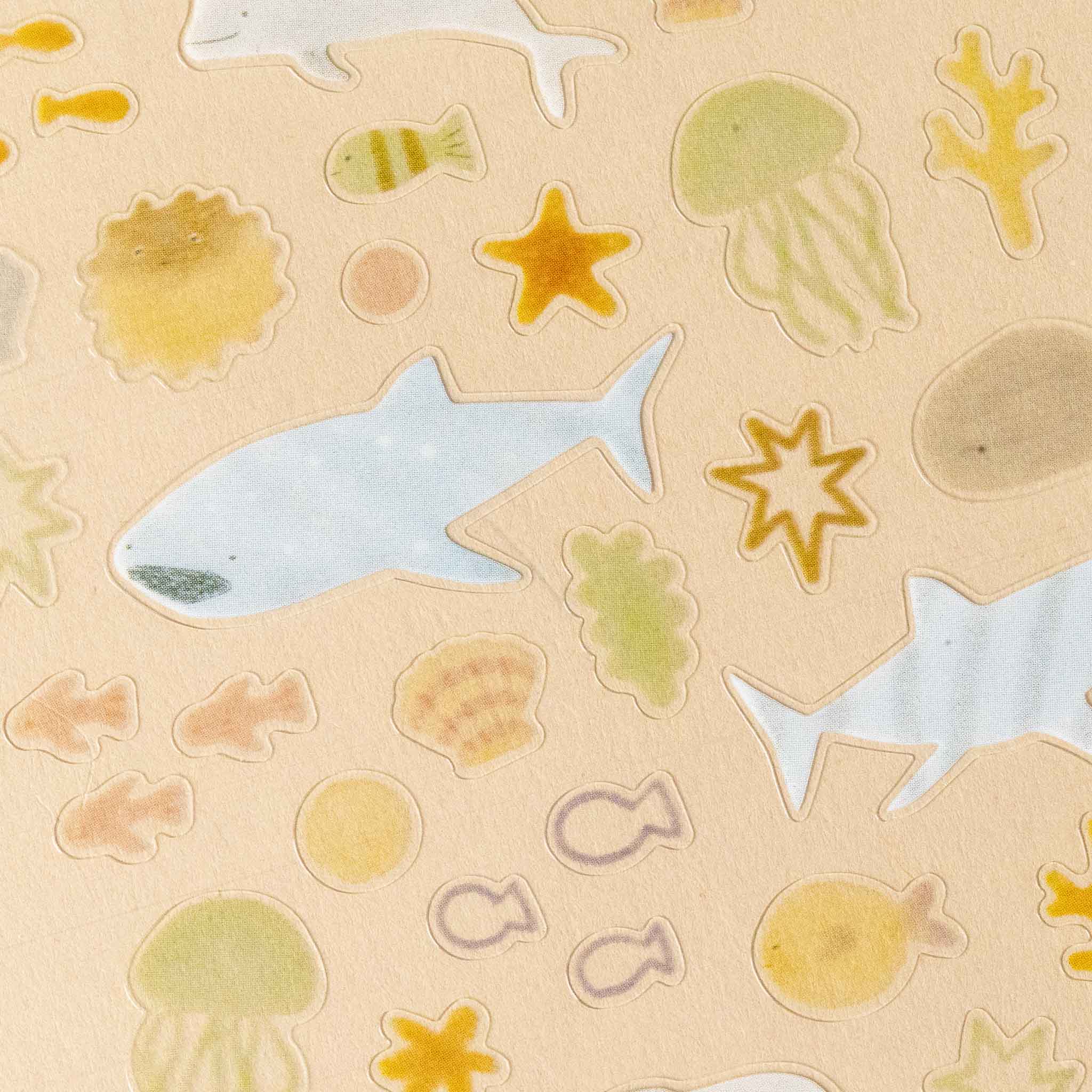 deco-sticker-sheet-aqua Pattern of sea-themed stickers including fish, starfish, and jellyfish on a beige background.