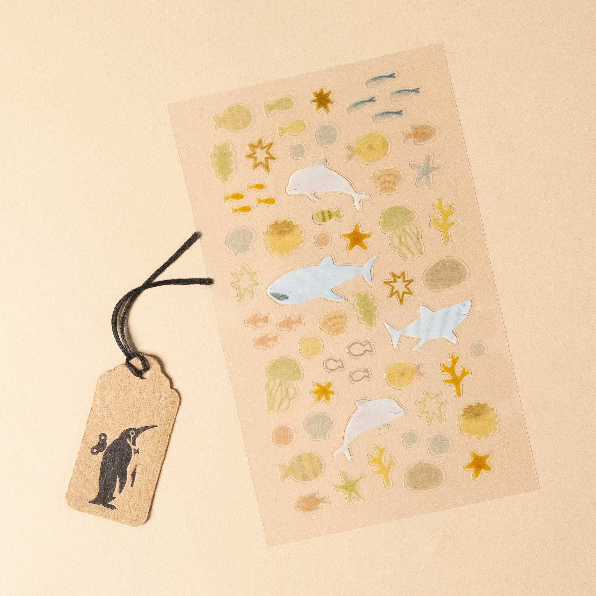 deco-sticker-sheet-aqua of ocean-themed stickers with a penguin tag on a beige background