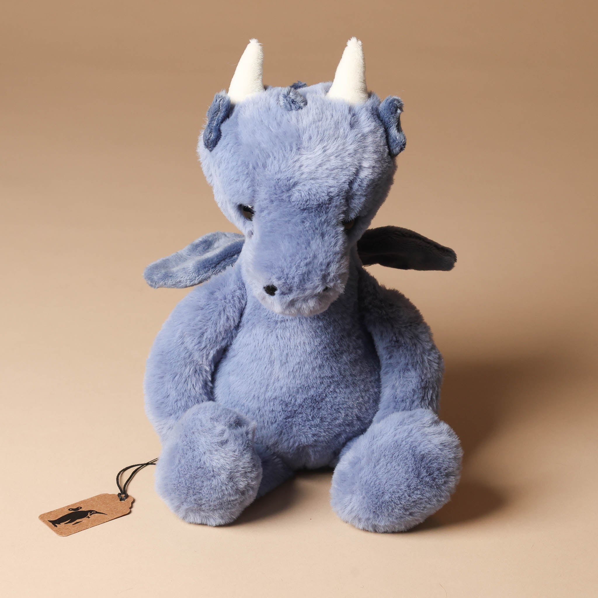 draco-dragon-denim Blue plush  toy with white horns on a beige background