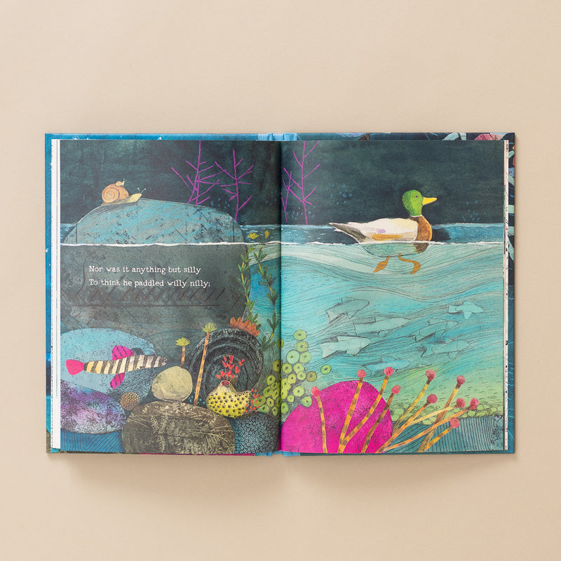 An open illustrated children's book laid flat on a warm beige background. The spread shows a colorful underwater scene with a duck on the water, fish, rocks, plants, and a small animal on a rock, with a line of text on the left page.