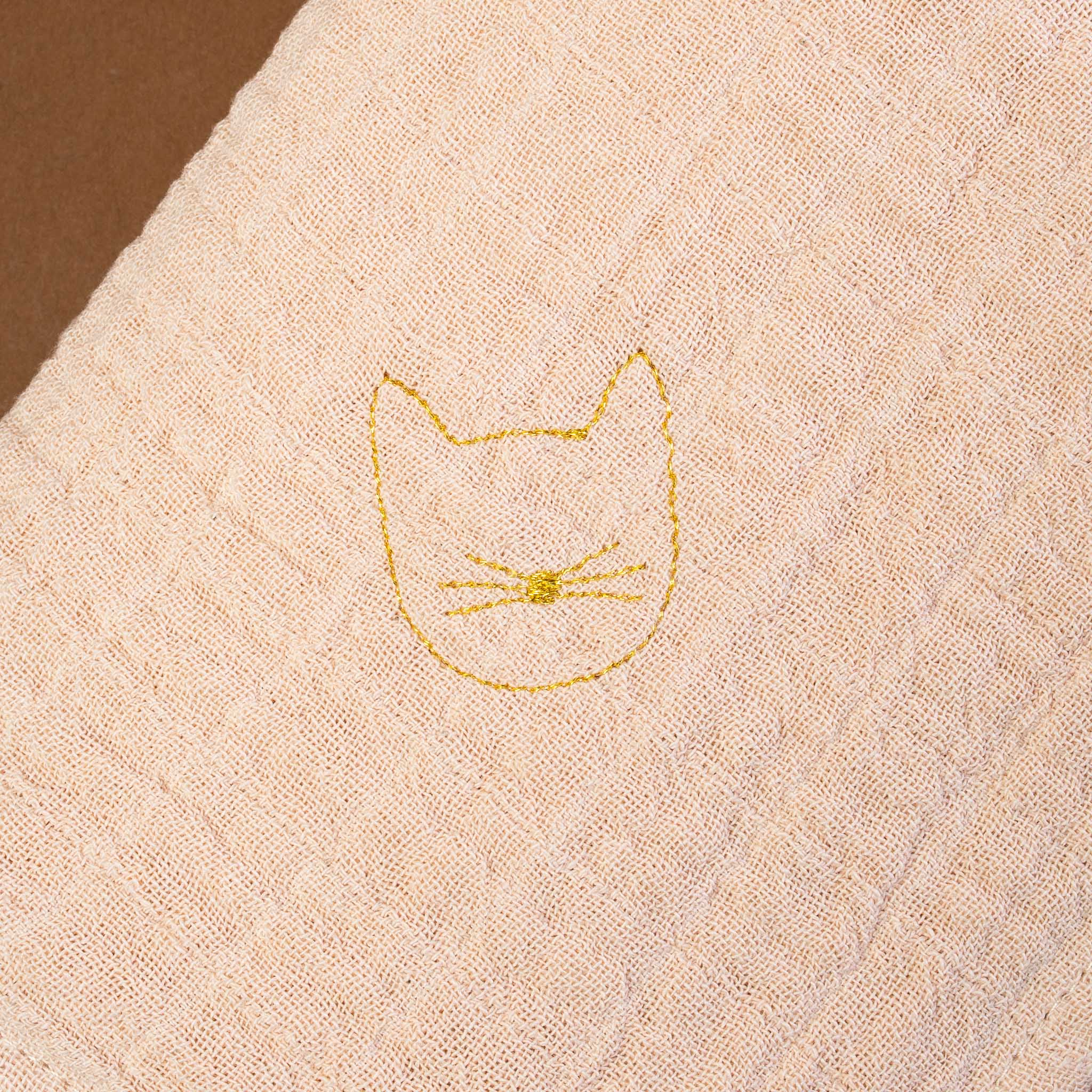 close-up-of-blush-fabric-with-gold-embroidered-kitten