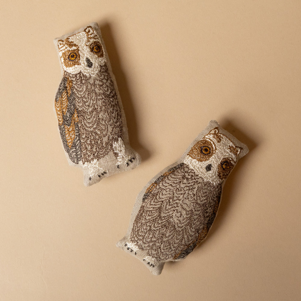 embroidered-pocket-pillow--mama-owl Two owlet-shaped pillows on a beige background