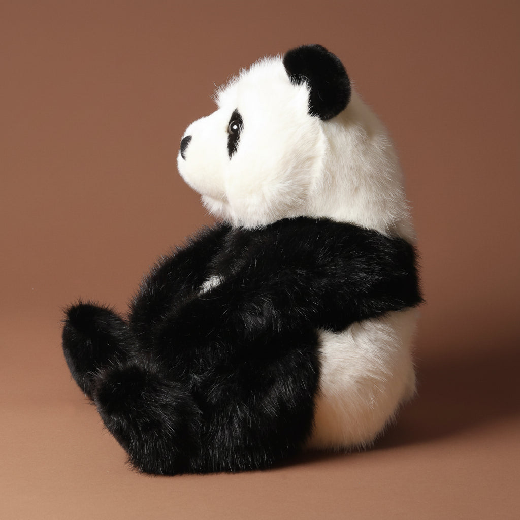 Plush emmet-the-panda-bear toy on a brown background