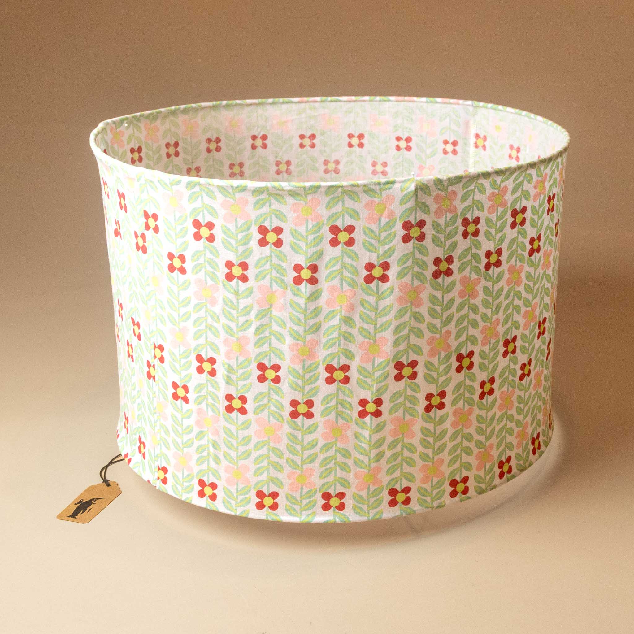 A fabric-lantern-bindweed_ with a retro floral pattern featuring pink, red, and yellow flowers with green leaves on a light background, shown on a warm beige background.