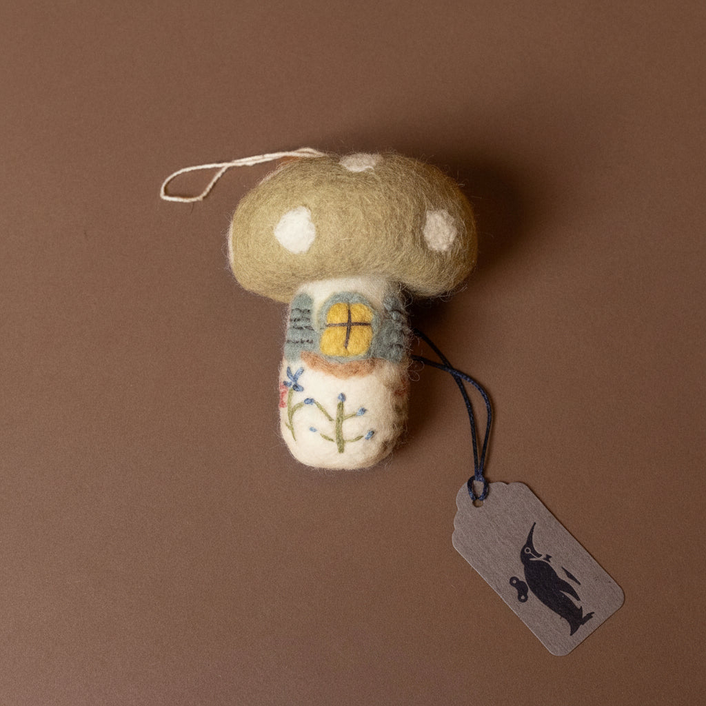 Felted mushroom ornament with a tag on a brown background