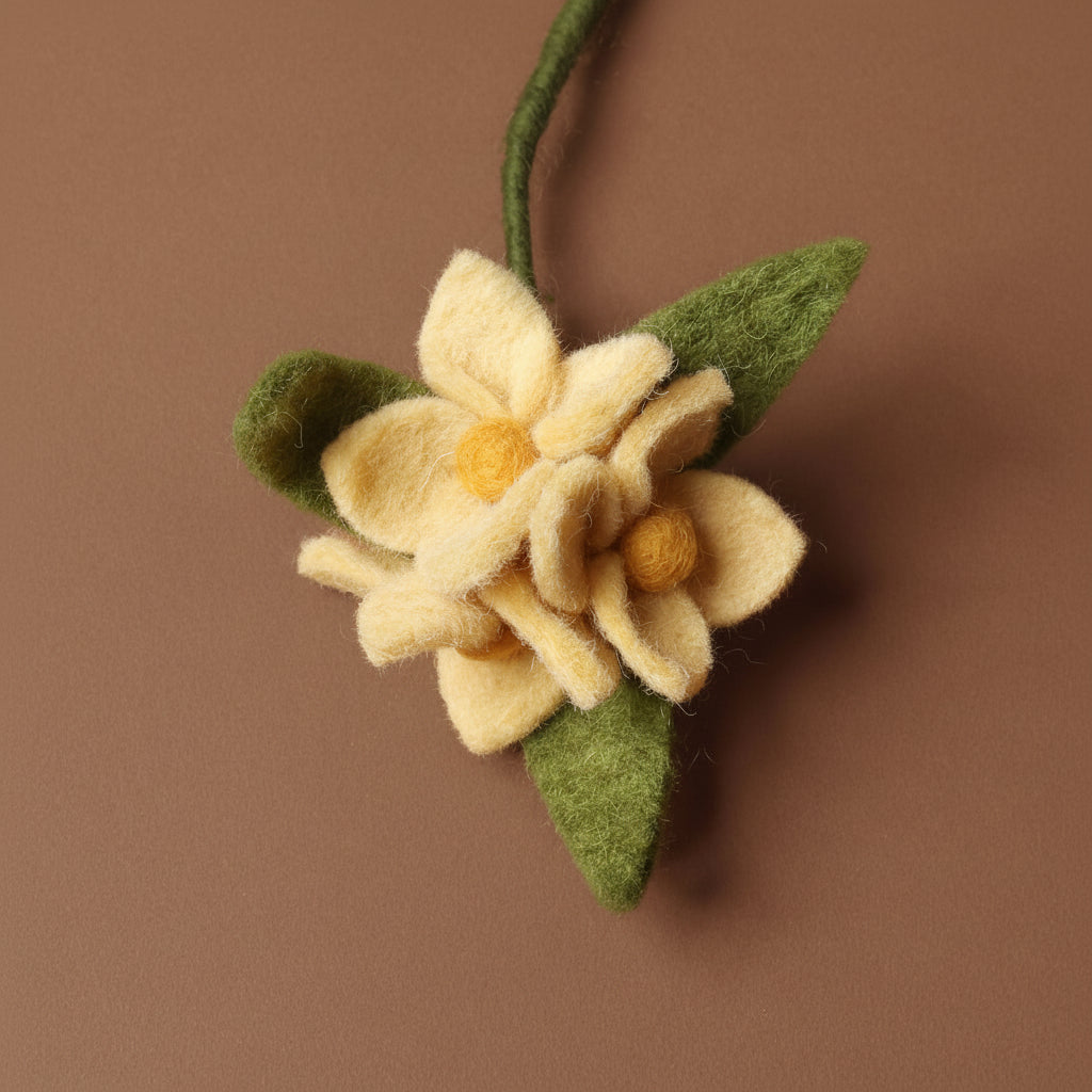 Felted flower with green leaves on a brown background