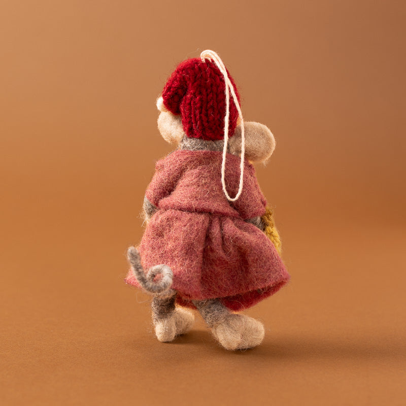 A felted wool mouse ornament wearing a red knit hat and pink dress with embroidered floral details, holding a yellow crocheted basket, 