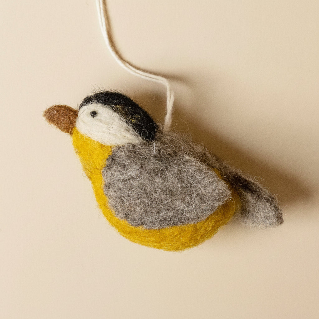 Felted bird ornament on a beige background