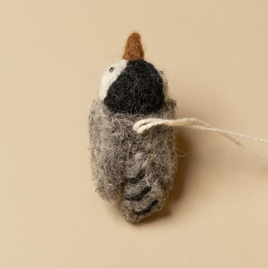 Felted wool ornament shaped like a bird on a beige background