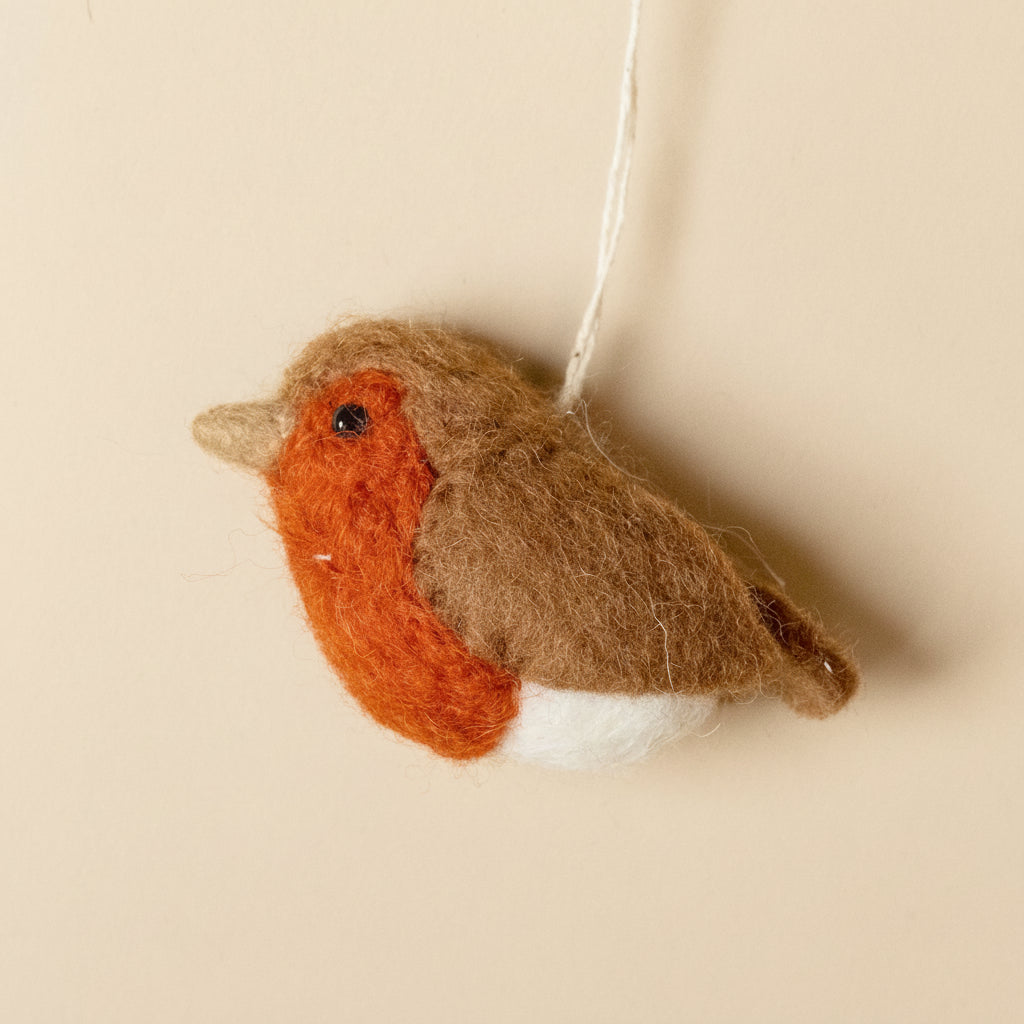 Felted robin decoration hanging against a beige background