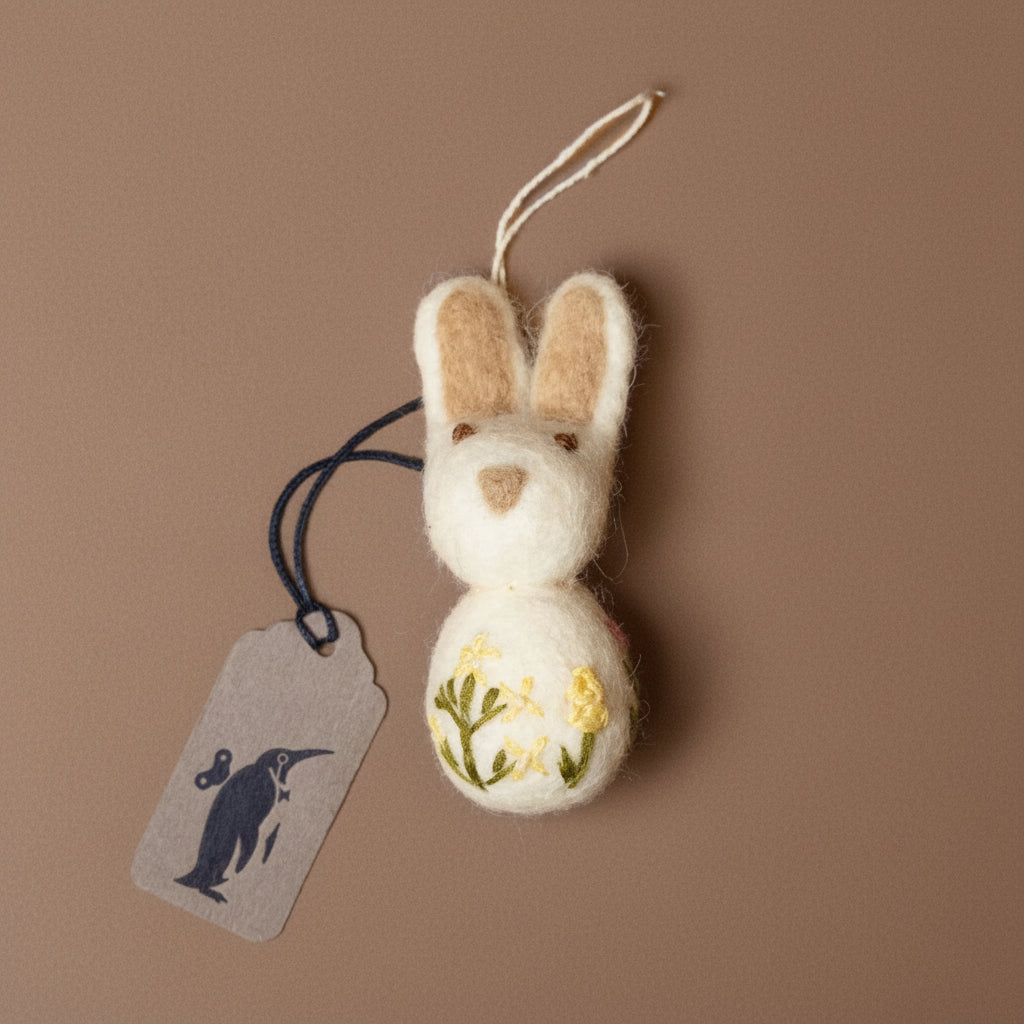 Felted rabbit ornament with floral design on a brown background
