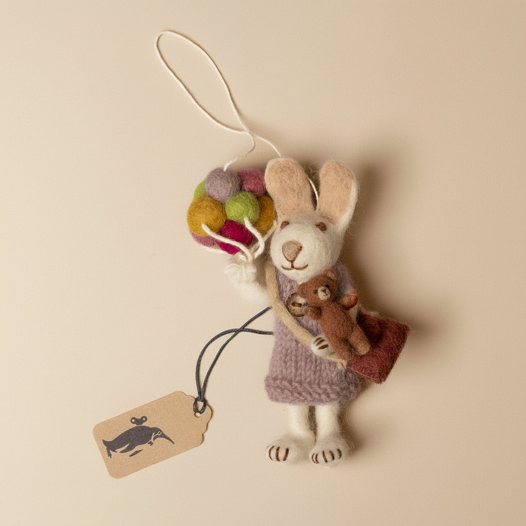 Felt rabbit ornament with colorful balloons and a tag on a beige background