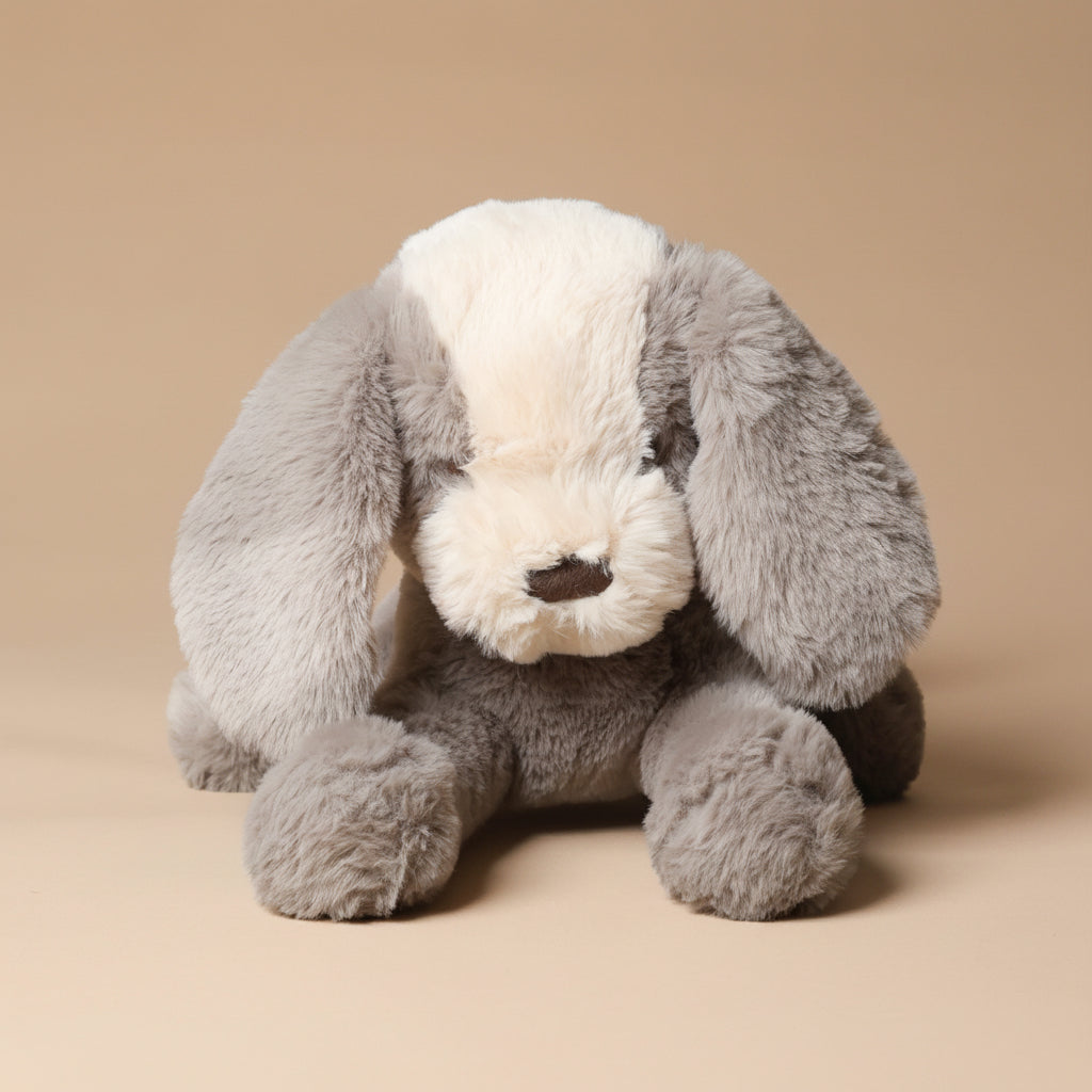 Gray plush floppy-mutt-steele toy on a beige background