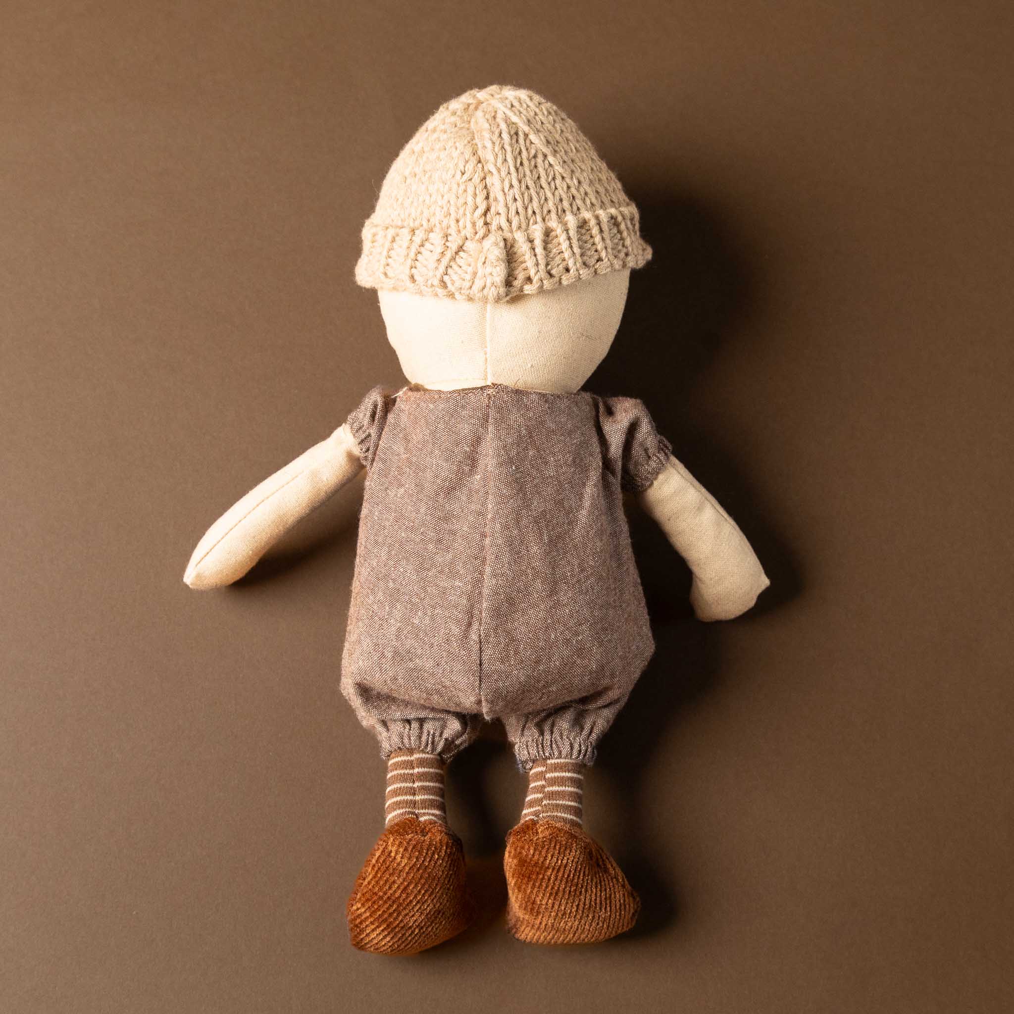 floyd-the-duck Stuffed animal wearing a knitted hat and overalls on a brown background