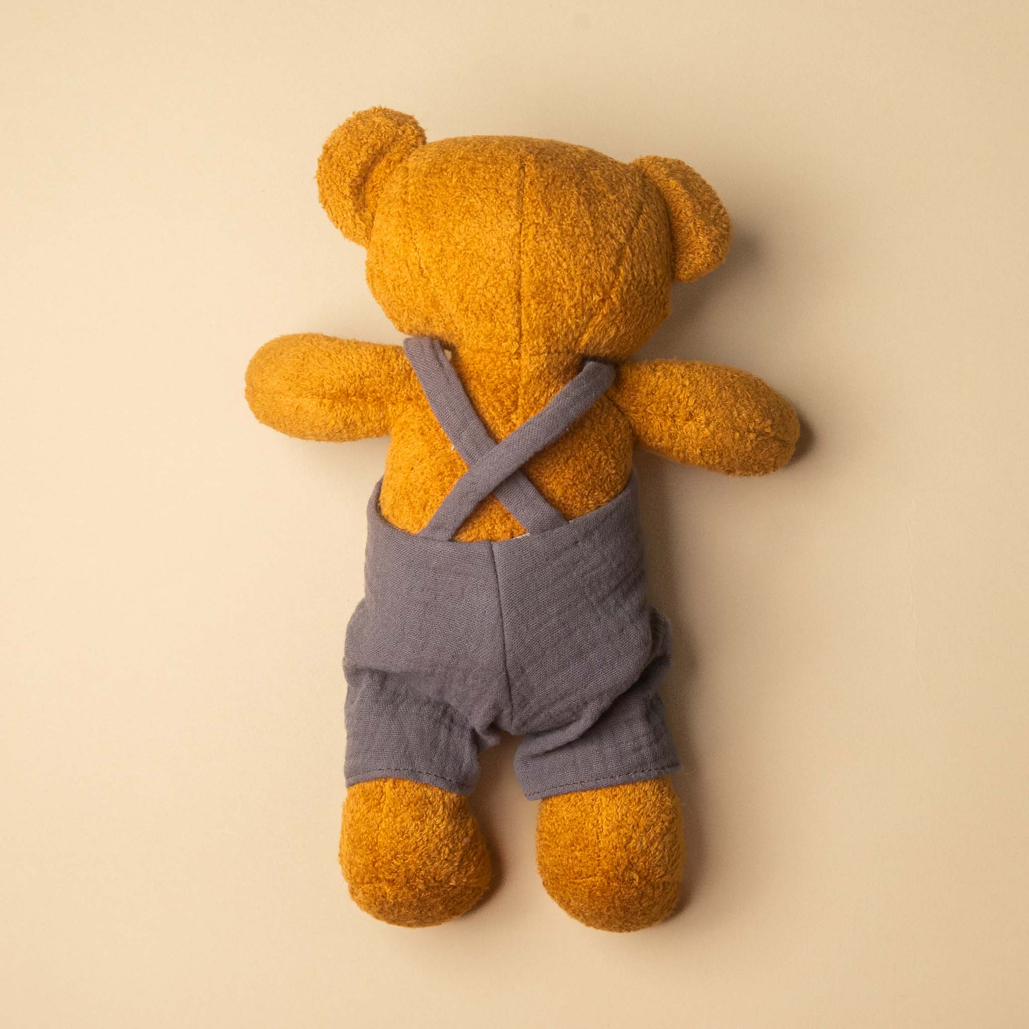 gabin-the-bear wearing gray overalls on a beige background