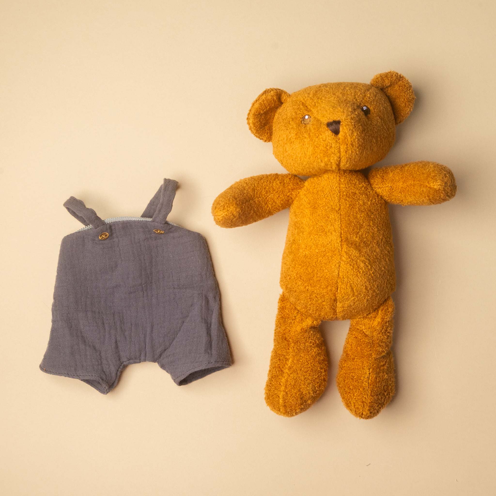 gabin-the-bear and blue baby romper on a beige background