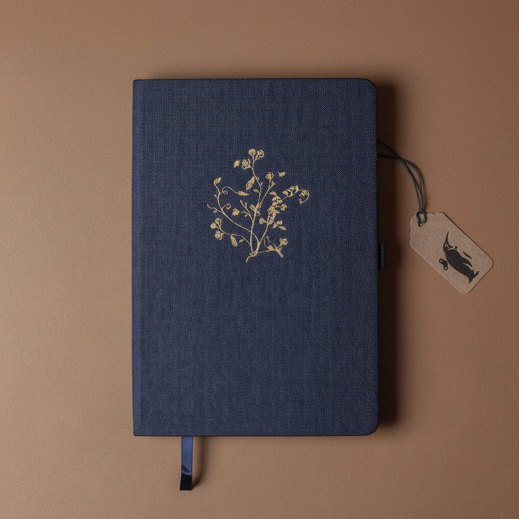Dark blue notebook with gold floral design and tag on a brown background