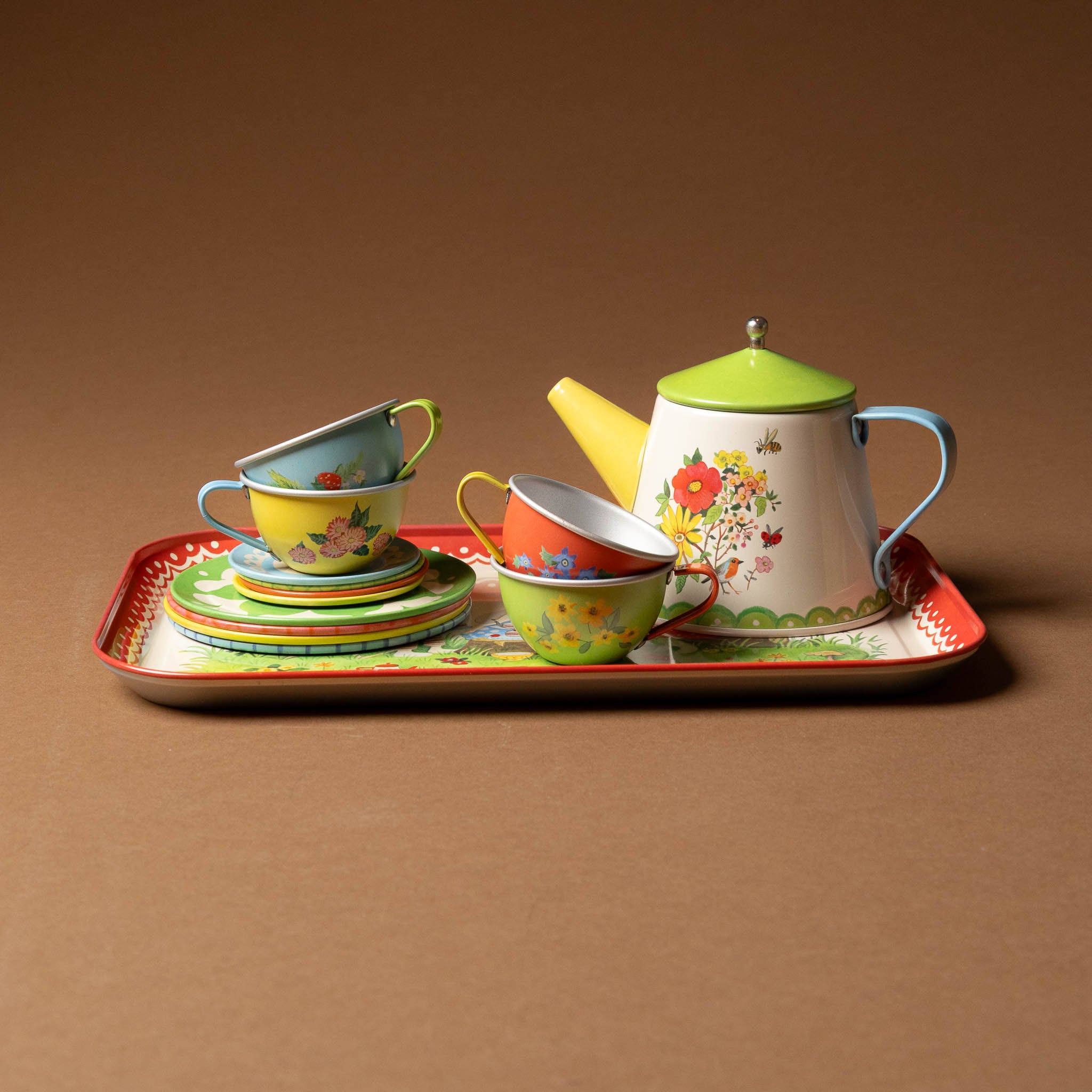 grande-famille-tea-set Colorful ceramic tea set with teapot, cups, and saucers on a tray against a brown background