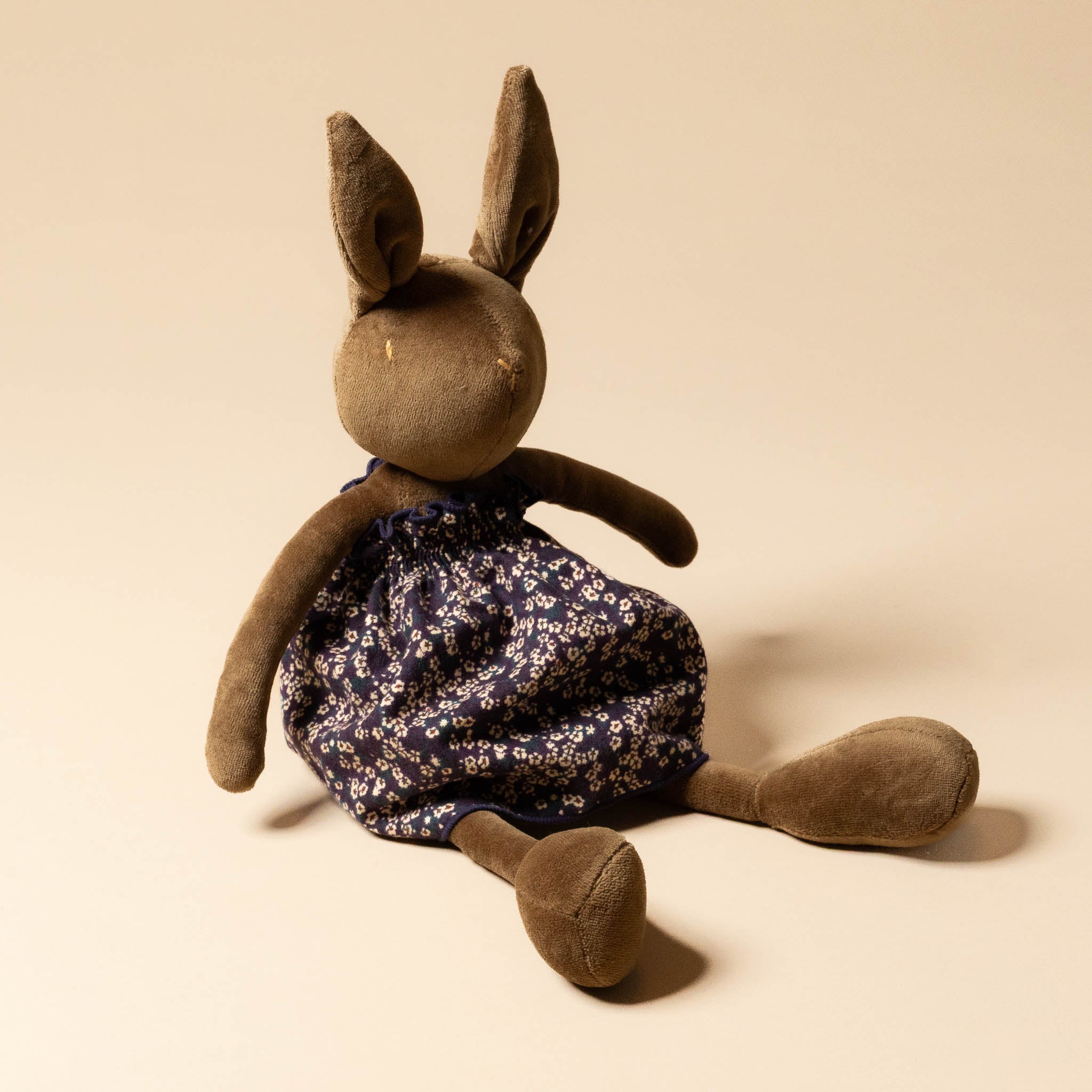 Brown stuffed animal wearing a grande-outfit-liberty-dress-midnight-floral on a beige background