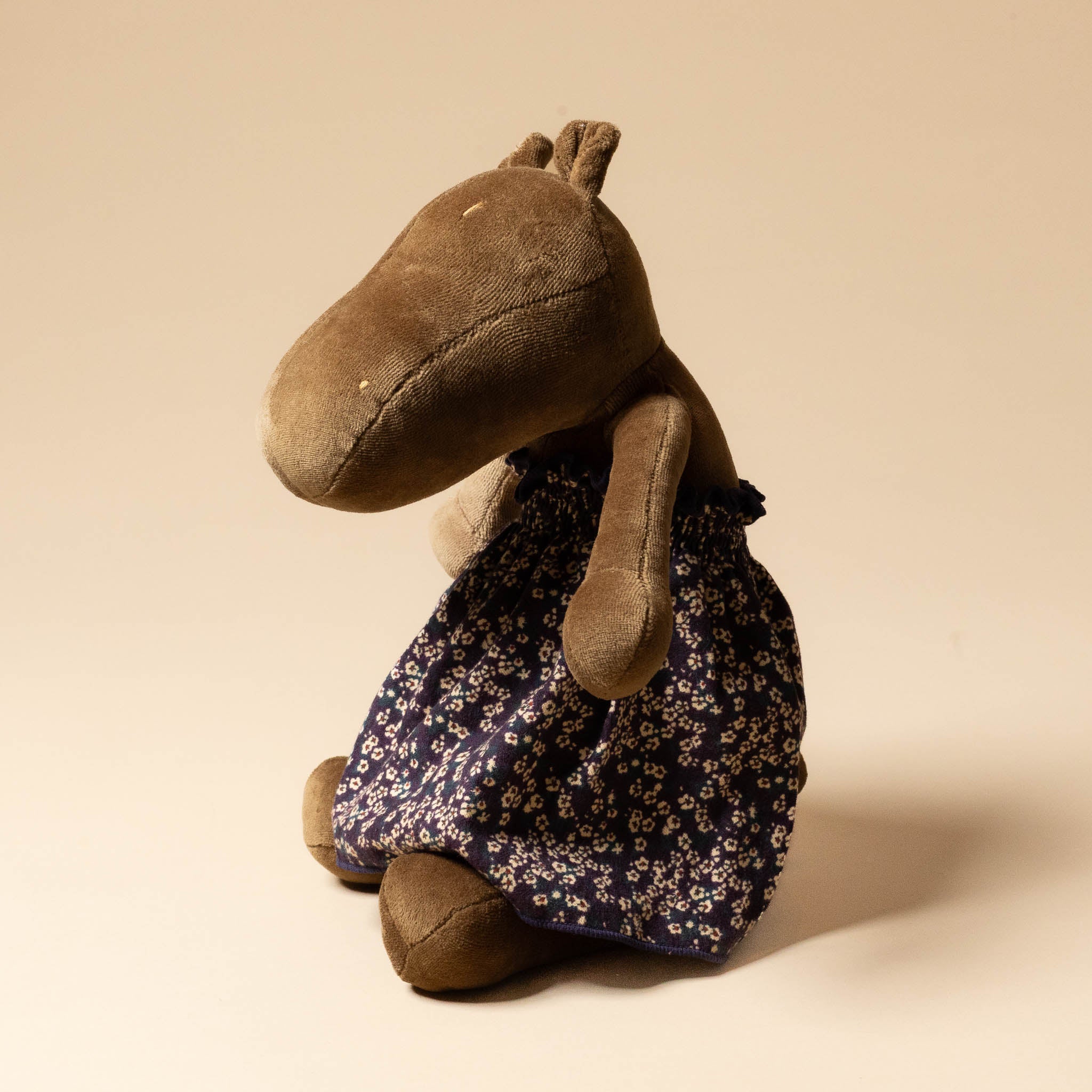 Brown plush toy with a grande-outfit-liberty-dress-midnight-floral on a beige background