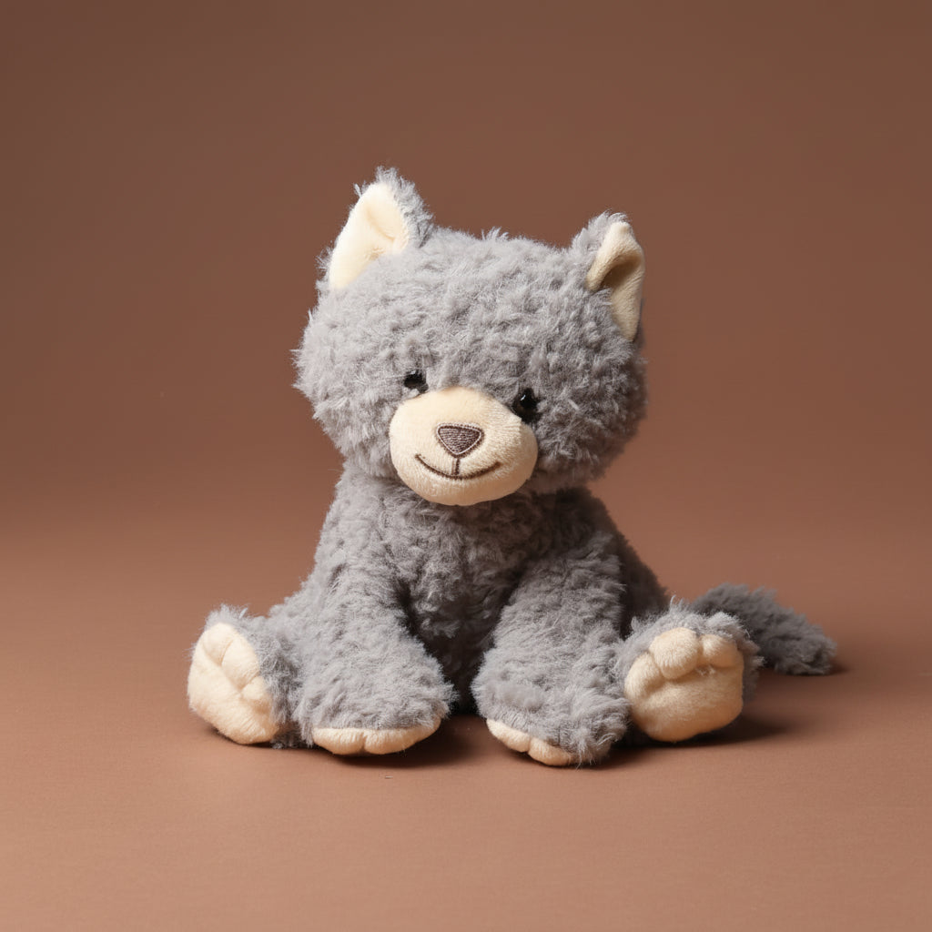 Gray plush grande-romy-the-cat--blueberry toy with a brown background