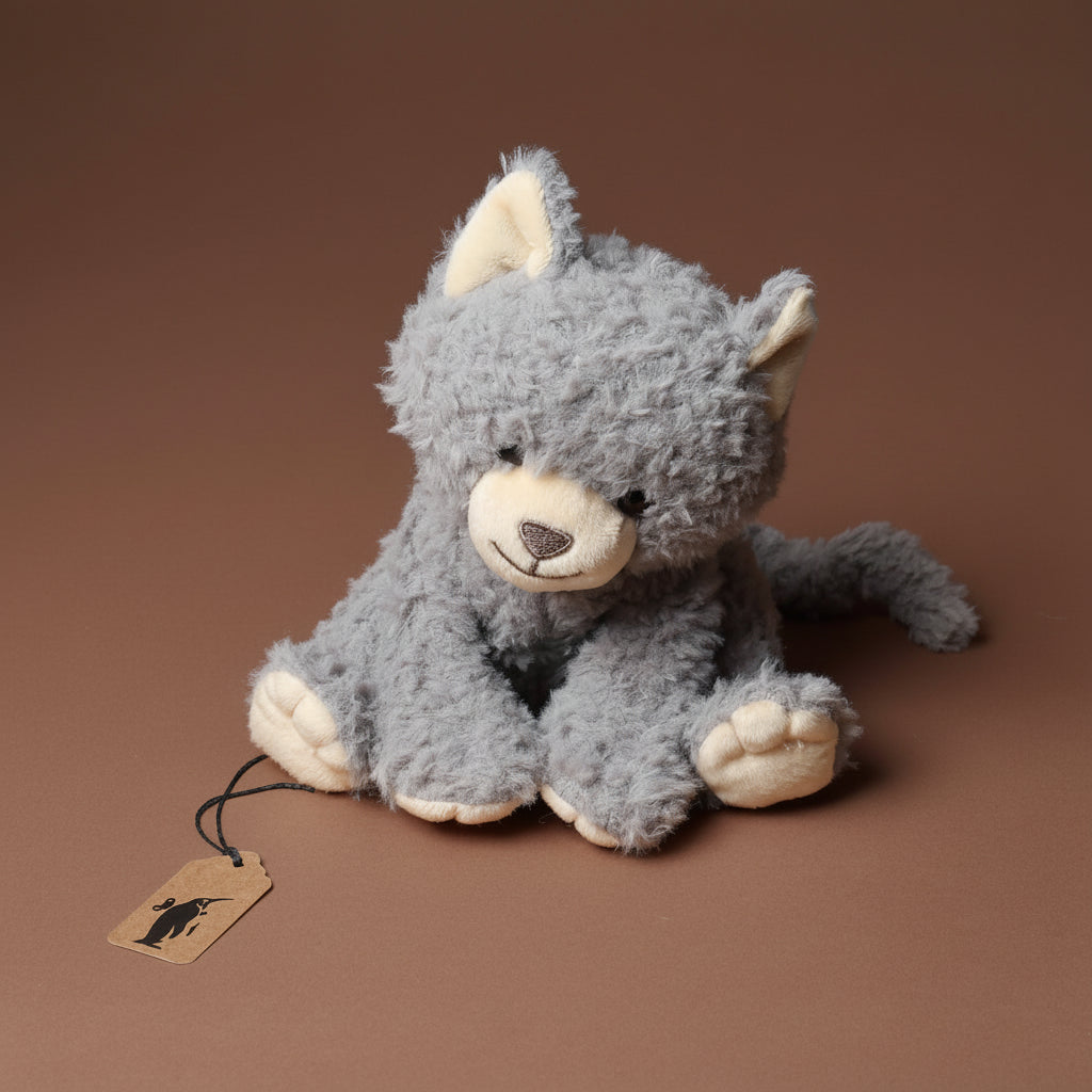 Gray plush grande-romy-the-cat--blueberry toy with a brown background