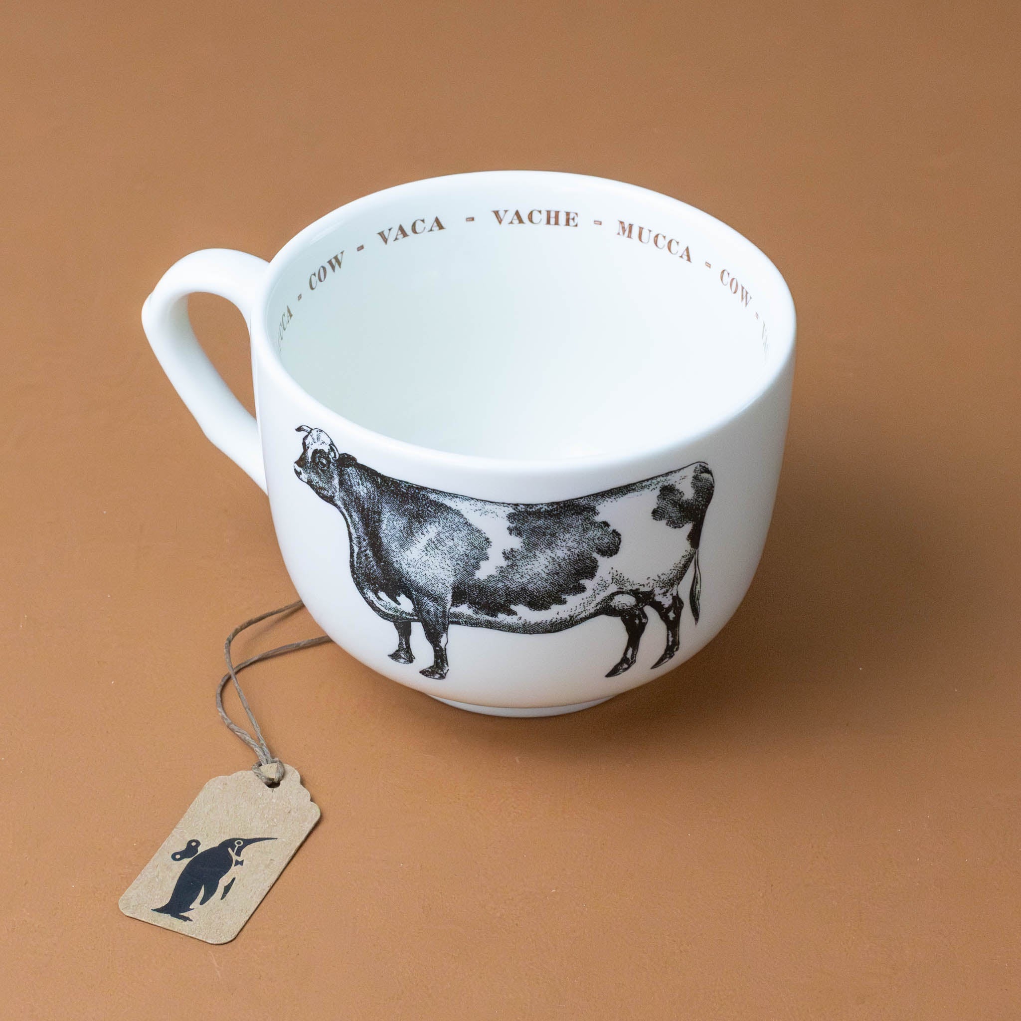 white-cup-grande-stoneware-cup-black-illustration-of-cow-with-the-word-cow-in-red-in-several-languages-on-interior