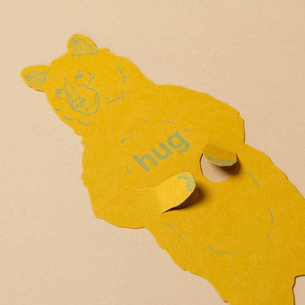 grizzly-bear-letterpress-gift-greeting-card Yellow bear-shaped card with 'hug' text on a beige background