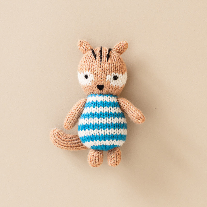 A small knitted squirrel plush toy wearing a blue and white striped shirt,