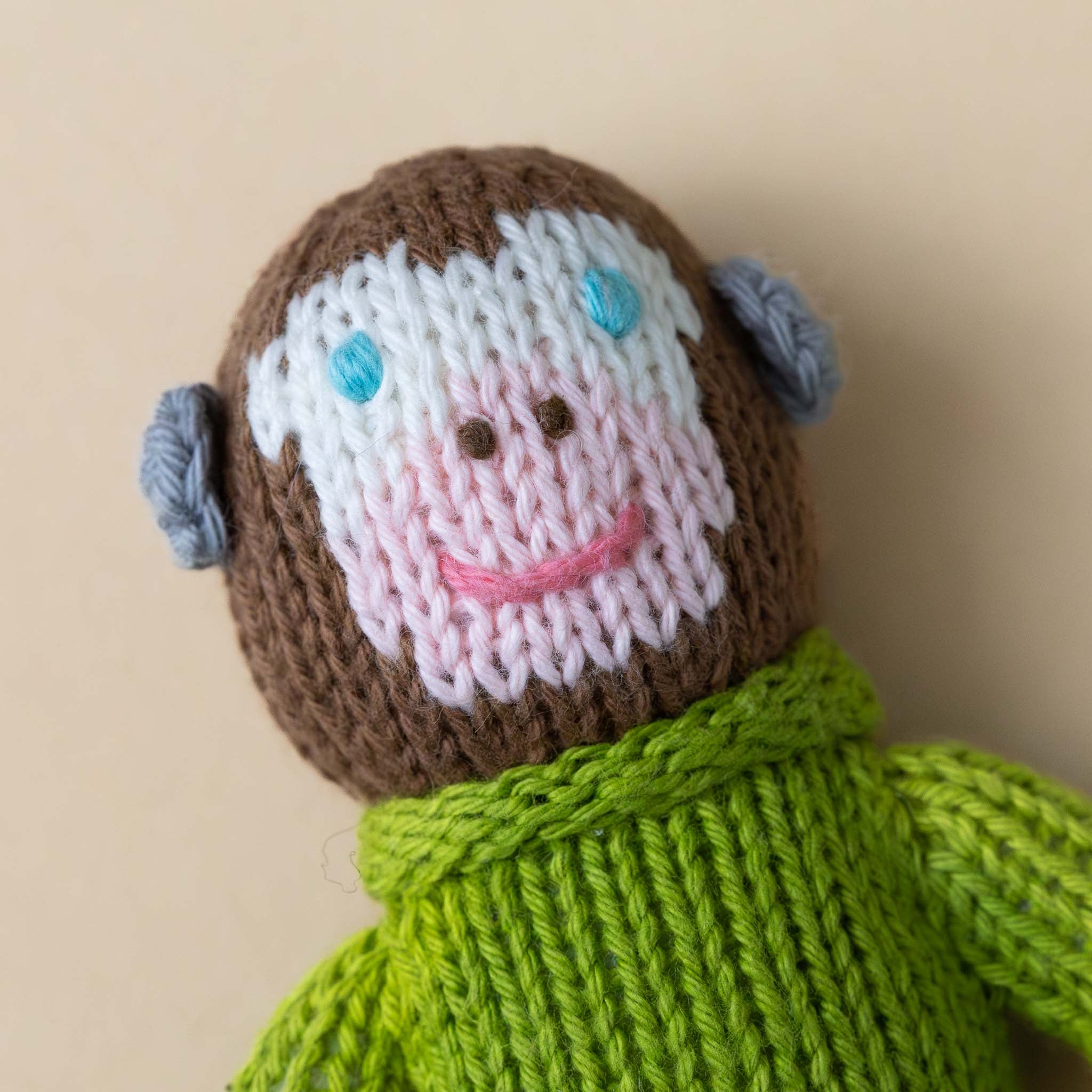 hand-knit-rattle-pierre-monkey-face-with-pink-snout-blue-eyes-and-smile