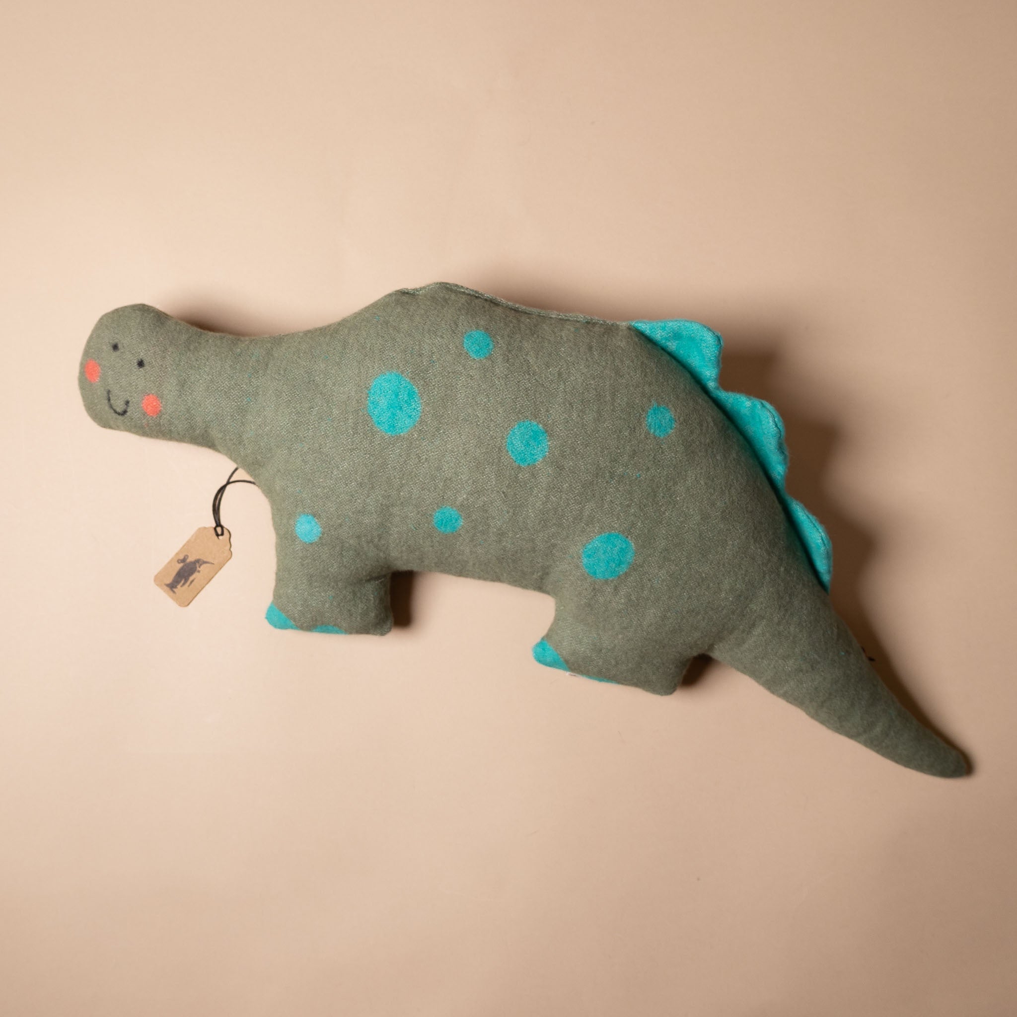 happy-dino-pillow Toy dinosaur with blue spots on a beige background