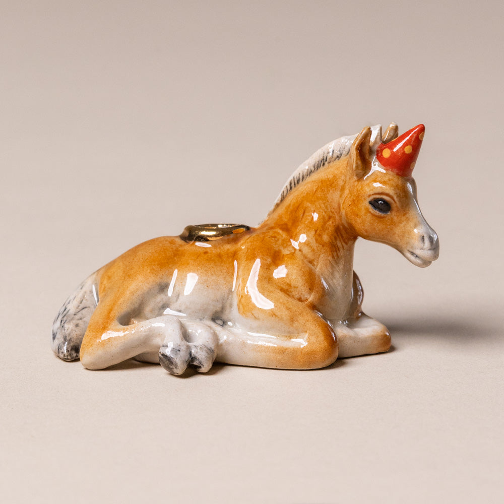 heirloom-porcelain-cake-topper-horse Ceramic horse figurine with a red horn on a beige background