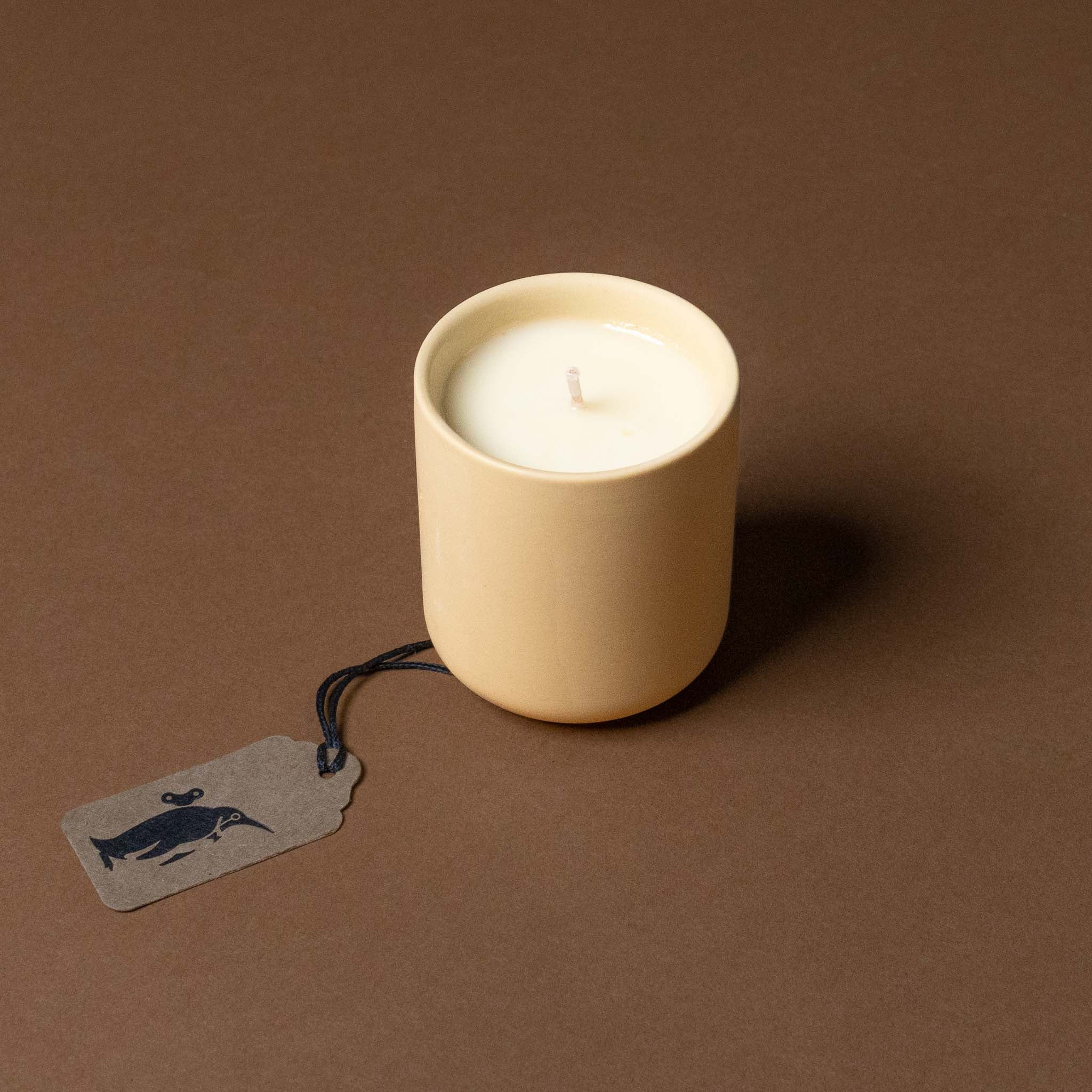 himalayan-cedarleaf-votive in a beige holder with a tag on a brown background