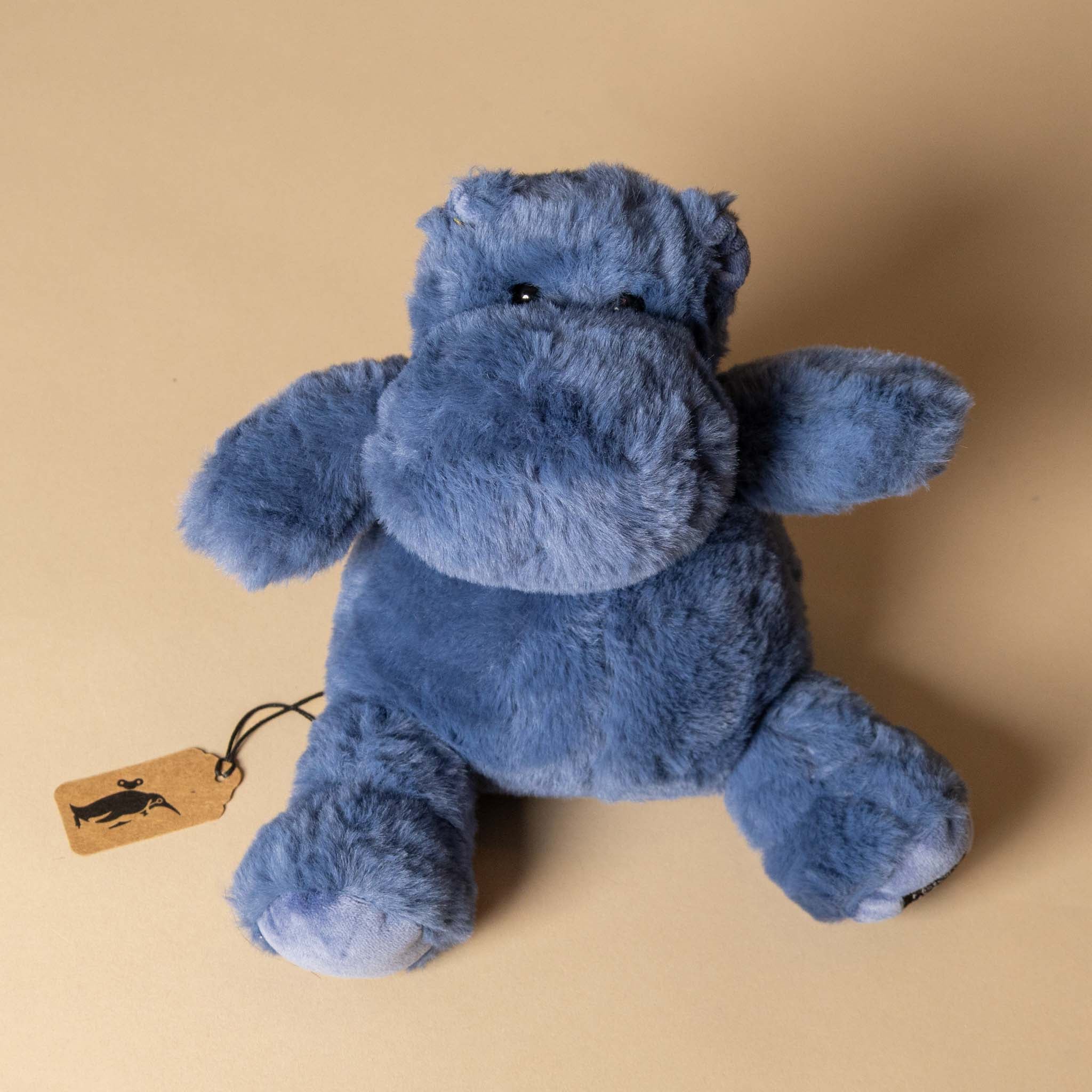 hip-hippo-ocean-blue-petite Blue plush hippo toy with a tag on a beige background