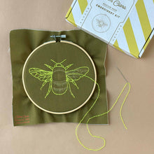 Load image into Gallery viewer, results after stitching: embroidered bee in yellow thread on green cloth.
