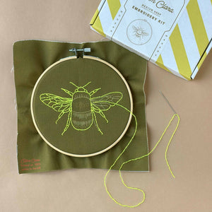 results after stitching: embroidered bee in yellow thread on green cloth.