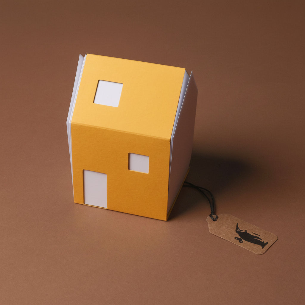 Yellow house-shaped object with a tag on a brown background