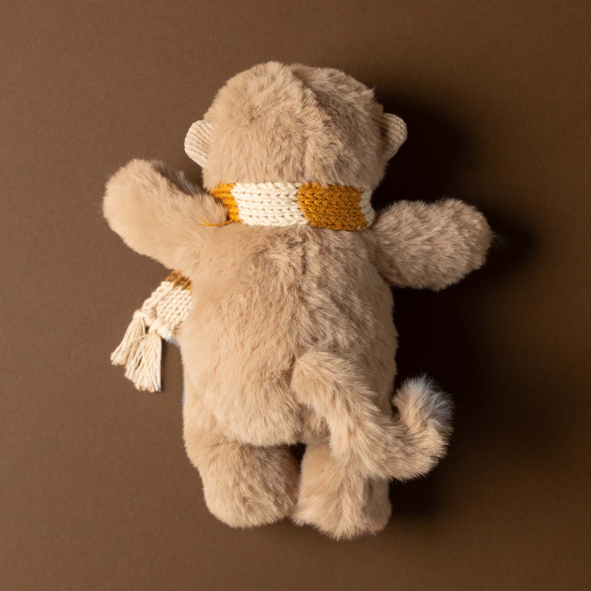 hugo-the-monkey Stuffed animal toy with a yellow scarf on a brown background